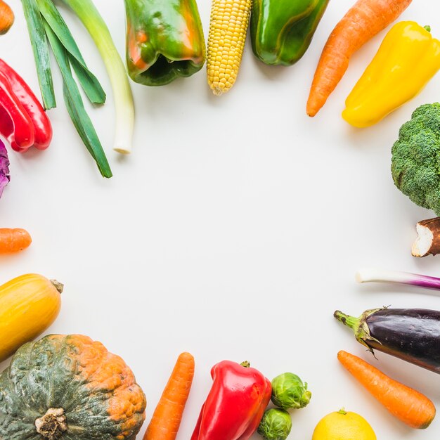 Elevated view of fresh vegetables forming circular frame on white backdrop