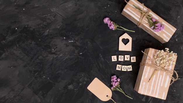 Elevated view of gift box; heart shape; flowers and price tag over black background