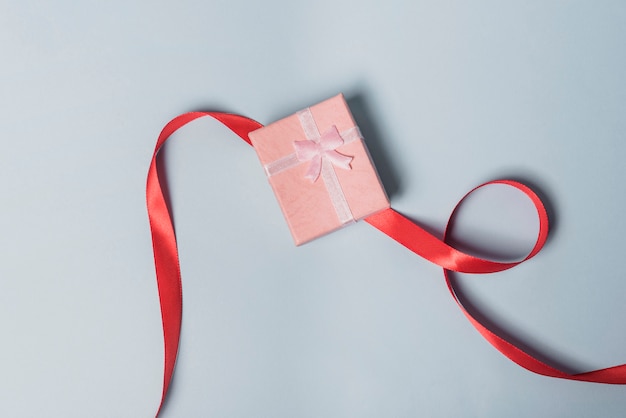 Elevated view of gift box with red ribbon on gray background