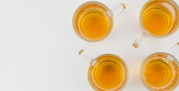 An elevated view of ginger tea in glass cups on white background