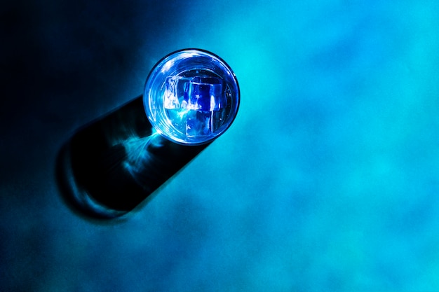 An elevated view of glass with shadow on blue backdrop