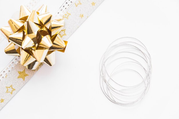 Elevated view of golden satin ribbon and silver string on white background