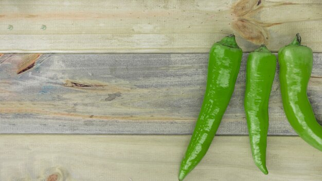 Elevated view of green chili peppers on wooden backdrop