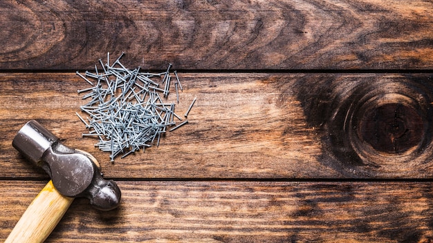 Elevated view of hammer with many bolts on wooden background