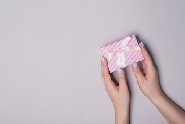 Elevated view of hand holding gift box against gray background