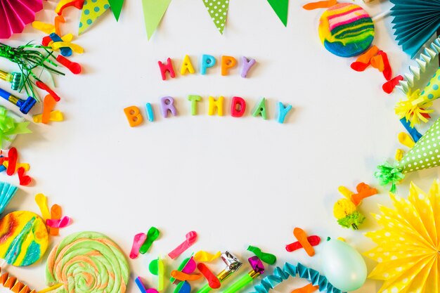 Elevated view of happy birthday text with party accessories on white surface