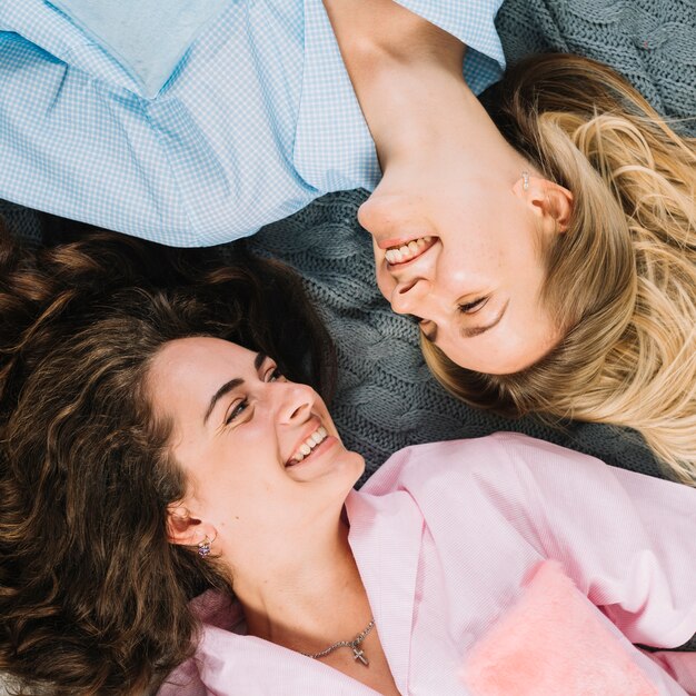 Elevated view of happy female friends lying on bed looking at each other