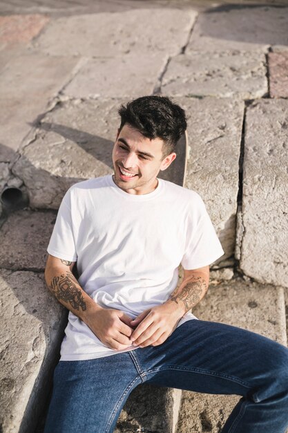 Elevated view of happy man leaning on skateboard