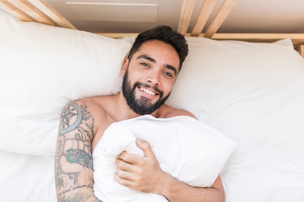 Elevated view of a happy man lying on bed with pillow