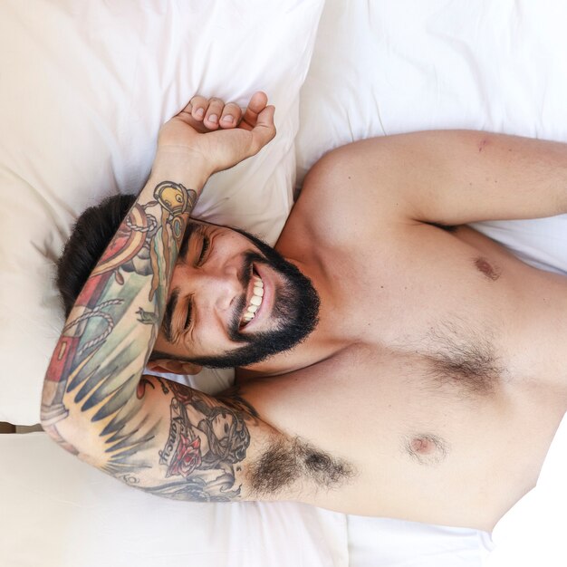 Elevated view of a happy young man lying on bed