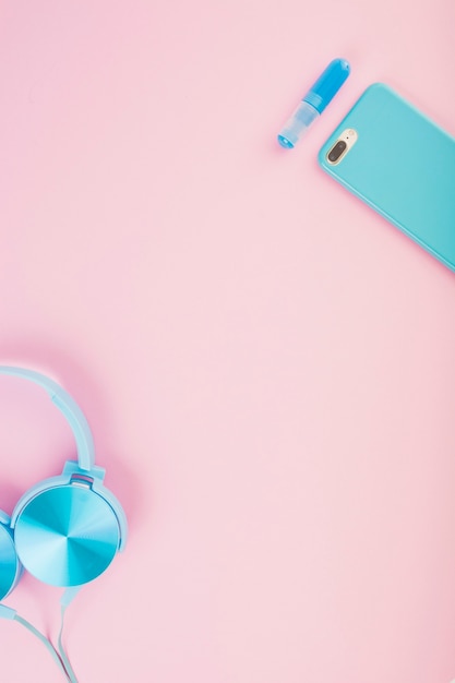 Elevated view of headphone and smartphone on pink background