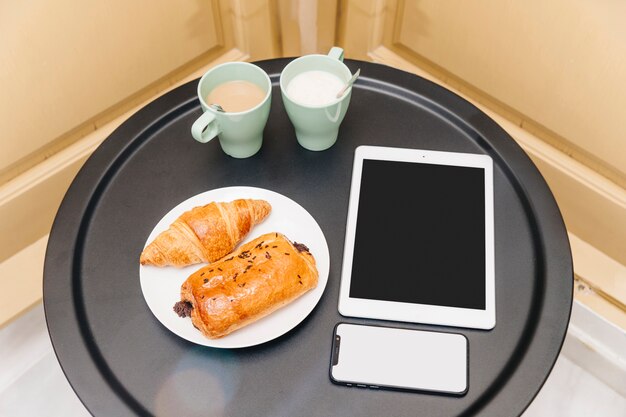 Elevated view of healthy breakfast with electronic gadgets on table