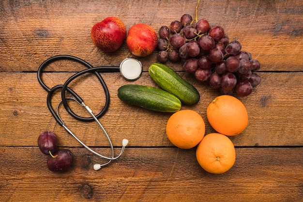 Elevated view of healthy fruits with stethoscope on wooden background