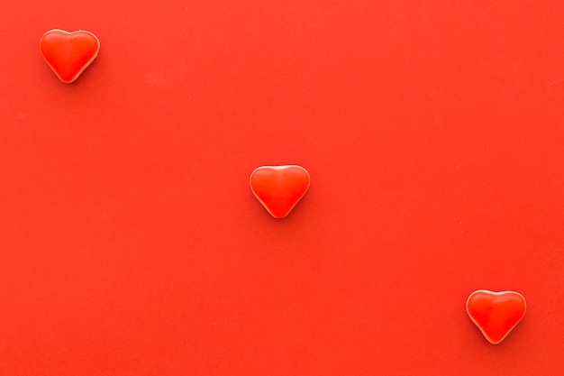 Elevated view of heart shape candies on red background