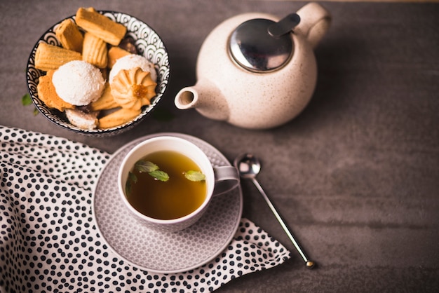 Elevated view of herbal tea; cookies and teapot on table