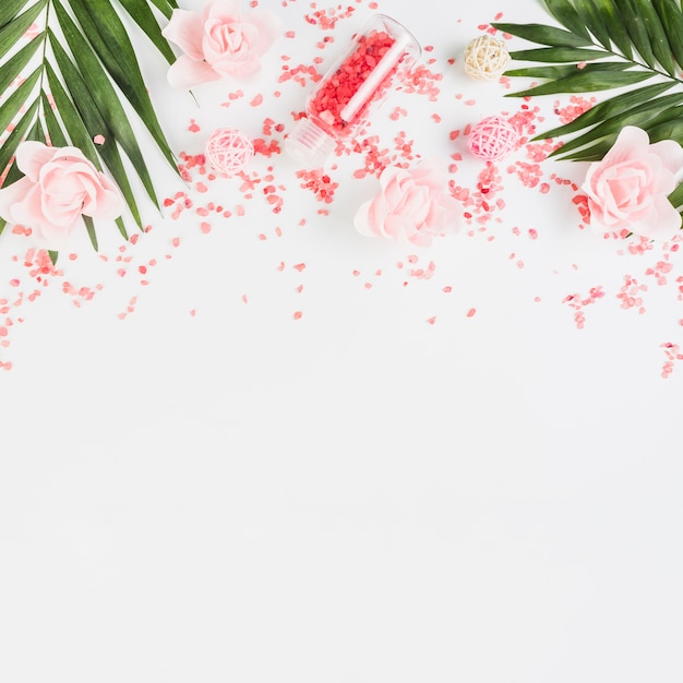 Elevated view of himalayan salt; leaves and flowers on white backdrop