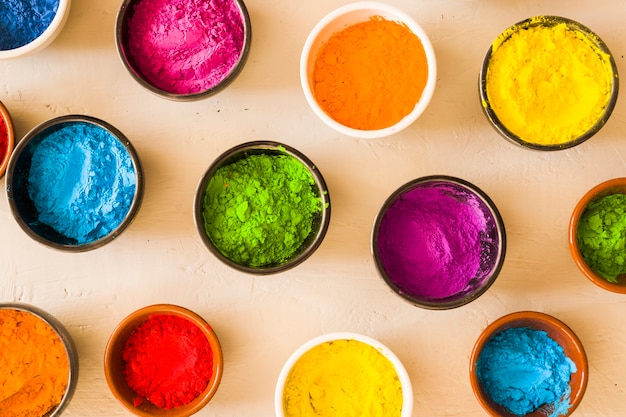 An elevated view of holi color powder in the different type of bowls on concrete backdrop