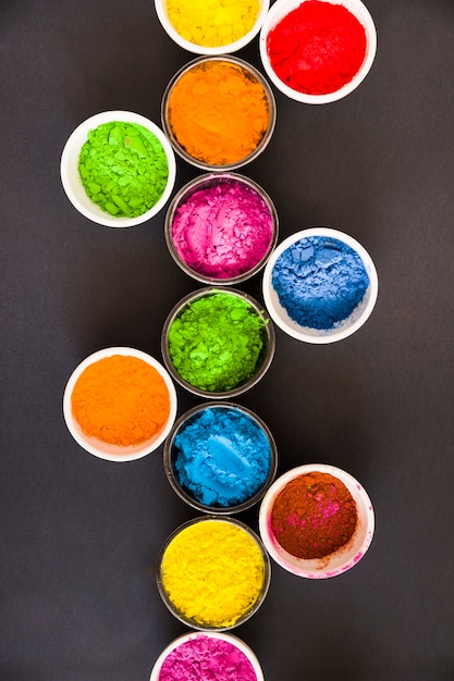 An elevated view of holi powder in the bowls on black background