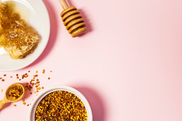 Free photo elevated view of honeycomb and bee pollen over pink surface