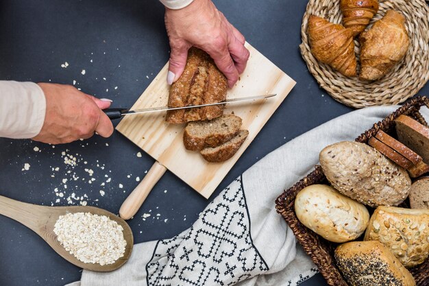 Elevated view of human hand slicing bread on chopping board