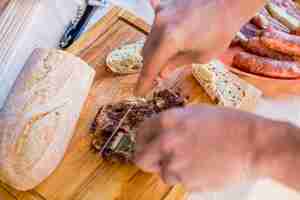 Free photo elevated view of a human hand slicing cooked meat on wooden chopping board