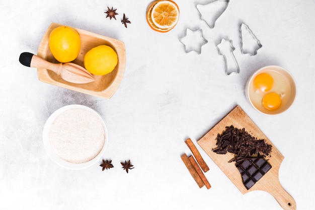 Free photo an elevated view of ingredients and pastry cutters on white textured background