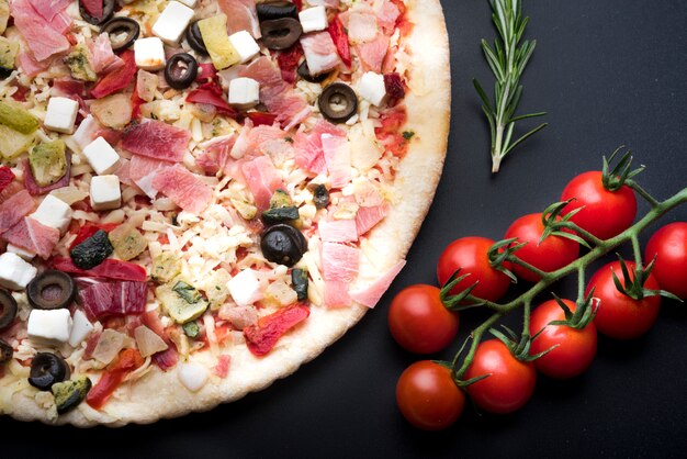 黒の表面にイタリアの新鮮なピザと食材の立面図