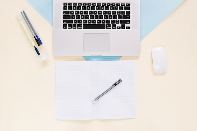 Elevated view of laptop and stationeries on colorful paper backdrop