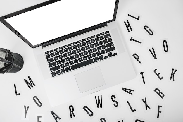 Повышенный вид ноутбука с различными алфавитами на белом фоне