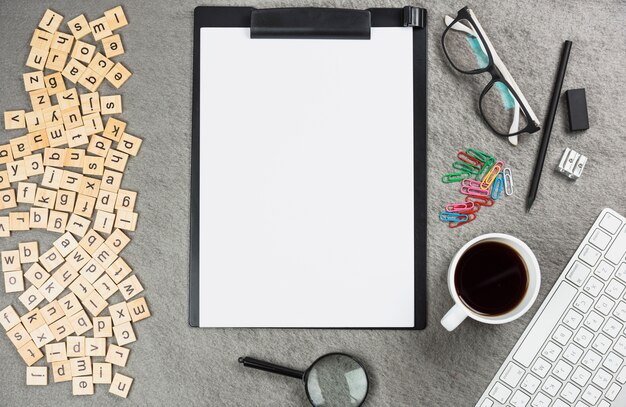 An elevated view of letter wooden blocks with office supplies on gray desk