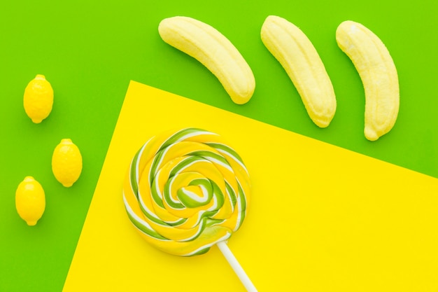 Elevated view of lollipop, banana and lemon cadies on multi colored background