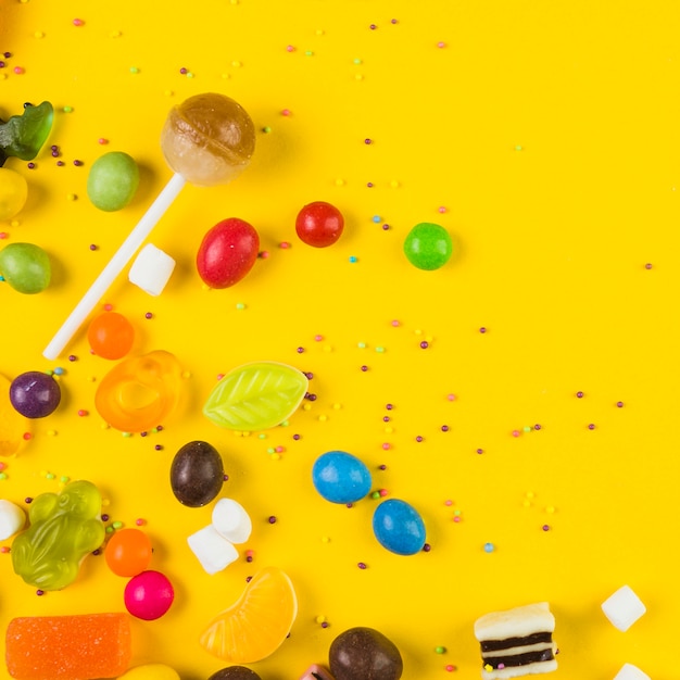 Elevated view of lollipop and candies on yellow background