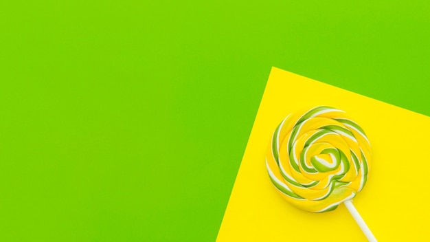 Elevated view of lollipop on dual yellow and green background