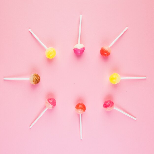 Elevated view of lollipops forming frame on pink backdrop