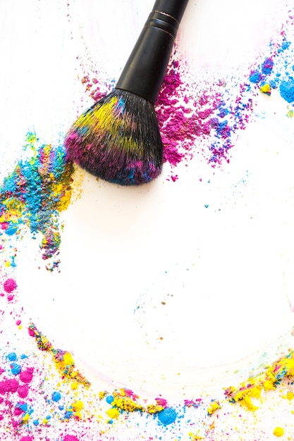 Free photo elevated view of make up brush and colorful compact powder on white background