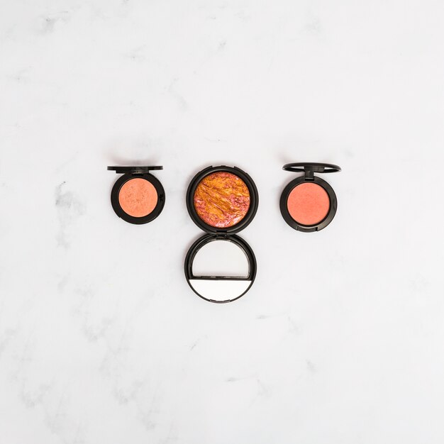 An elevated view of make-up face powder on marble textured backdrop