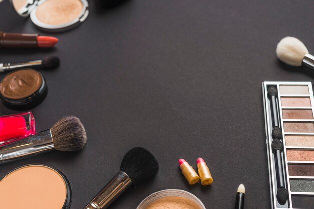 Elevated view of makeup brushes and cosmetic products on black backdrop