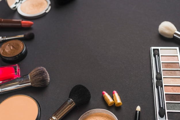 Elevated view of makeup brushes and cosmetic products on black backdrop