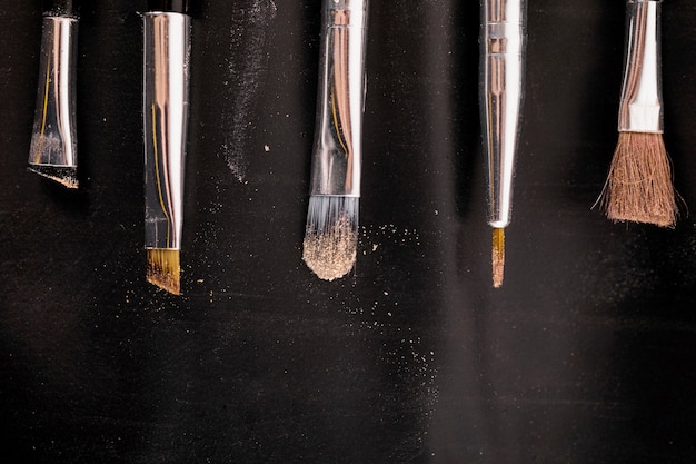 Elevated view of makeup brushes in a row on black backdrop