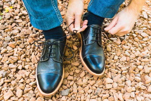 An elevated view of man's foot on pebble tying shoelace