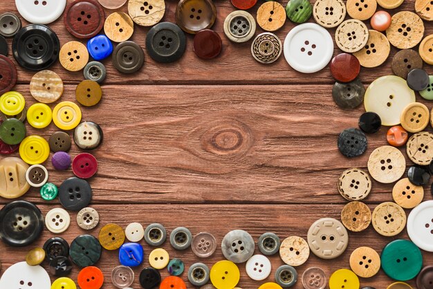 Elevated view of many buttons forming circle on wooden plank