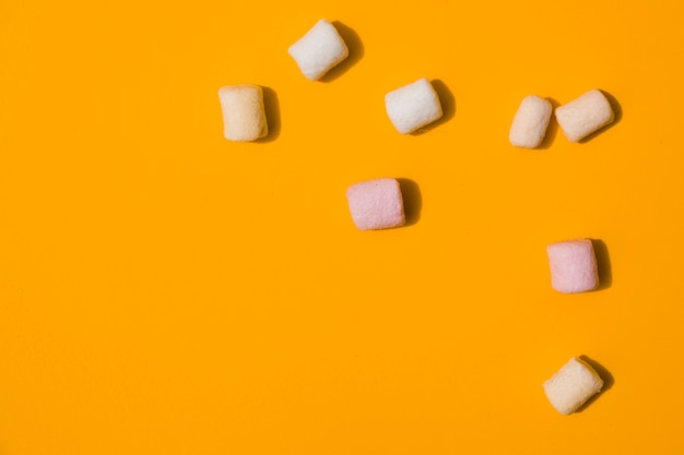 Free photo an elevated view of marshmallows on an orange backdrop