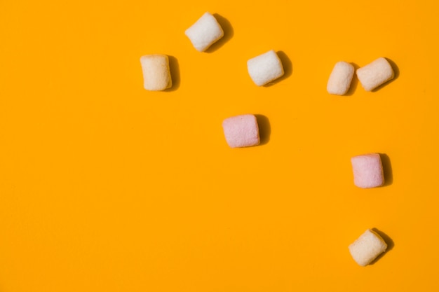 An elevated view of marshmallows on an orange backdrop