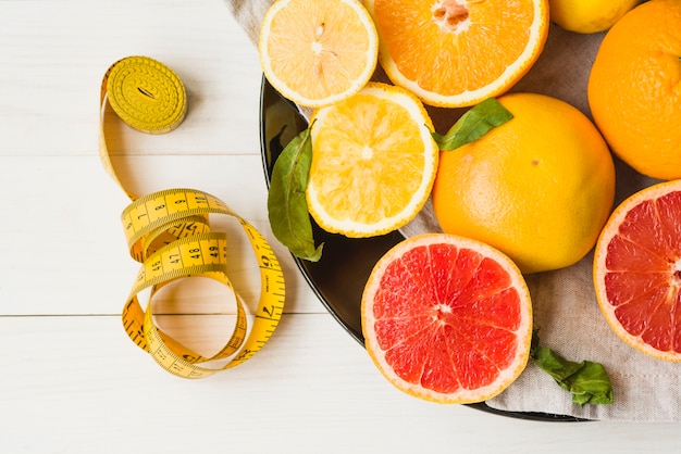 Free photo elevated view of measuring tape and citrus fruits on plate