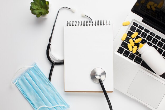 Elevated view of medical equipment and pills with open laptop