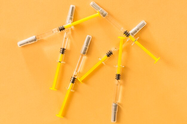 Elevated view of medical syringes on yellow background