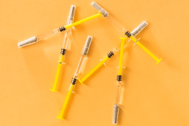 Повышенный вид медицинских шприцев на желтом фоне