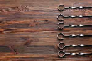 Free photo elevated view of metallic skewer arranged in row on wooden backdrop