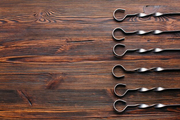 Elevated view of metallic skewer arranged in row on wooden backdrop