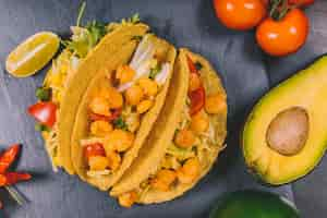 Free photo elevated view of mexican corn tacos with vegetables and avocado on black slate